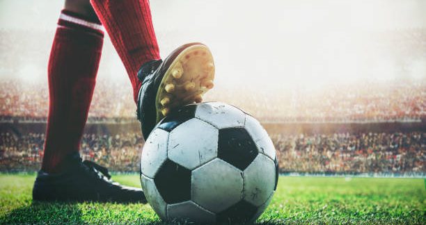 feet of soccer player tread on soccer ball for kick-off in the stadium